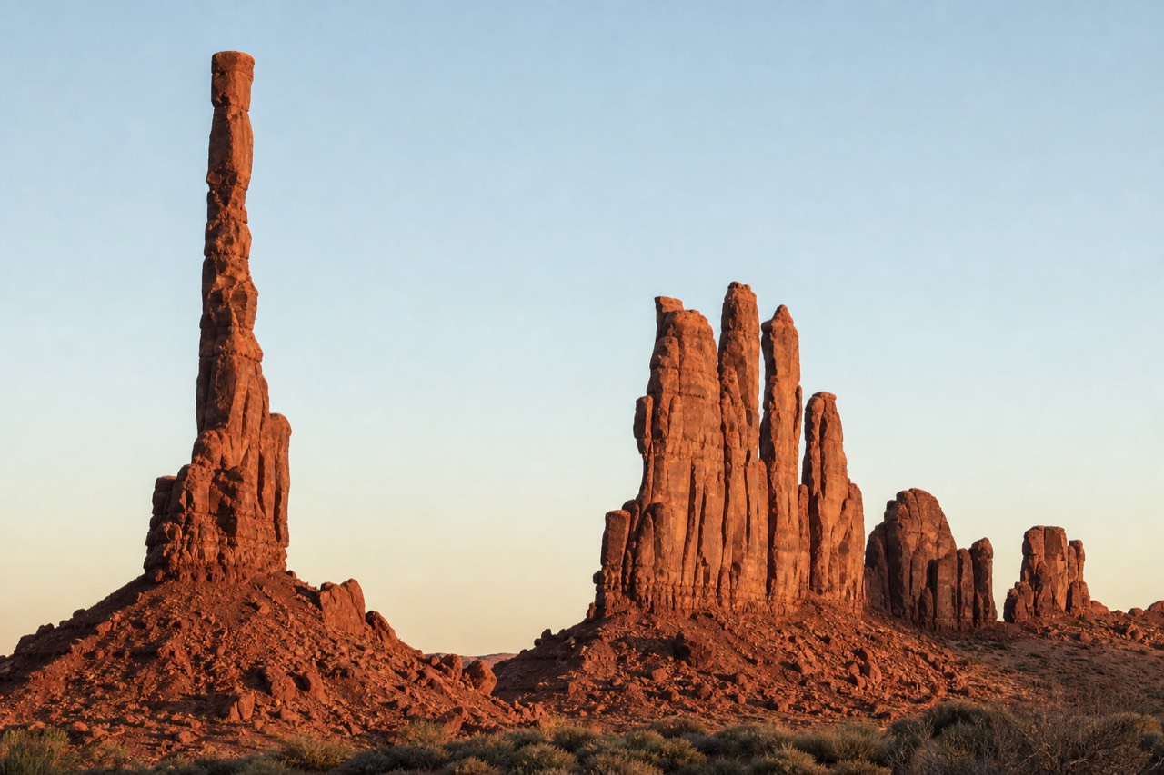 The slender Totem Pole spire and the Yei Bi Chei formations in Monument Valley at golden hour