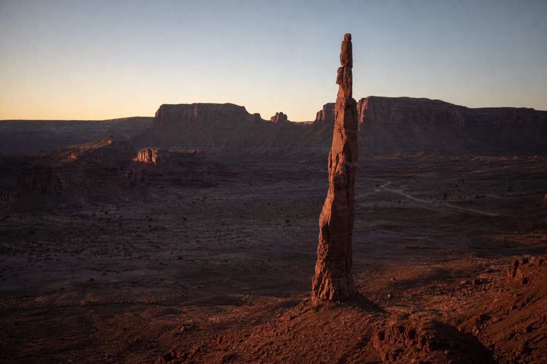 The thin Totem Pole spire rising alone from the empty backcountry sand at dawn with deep shadows