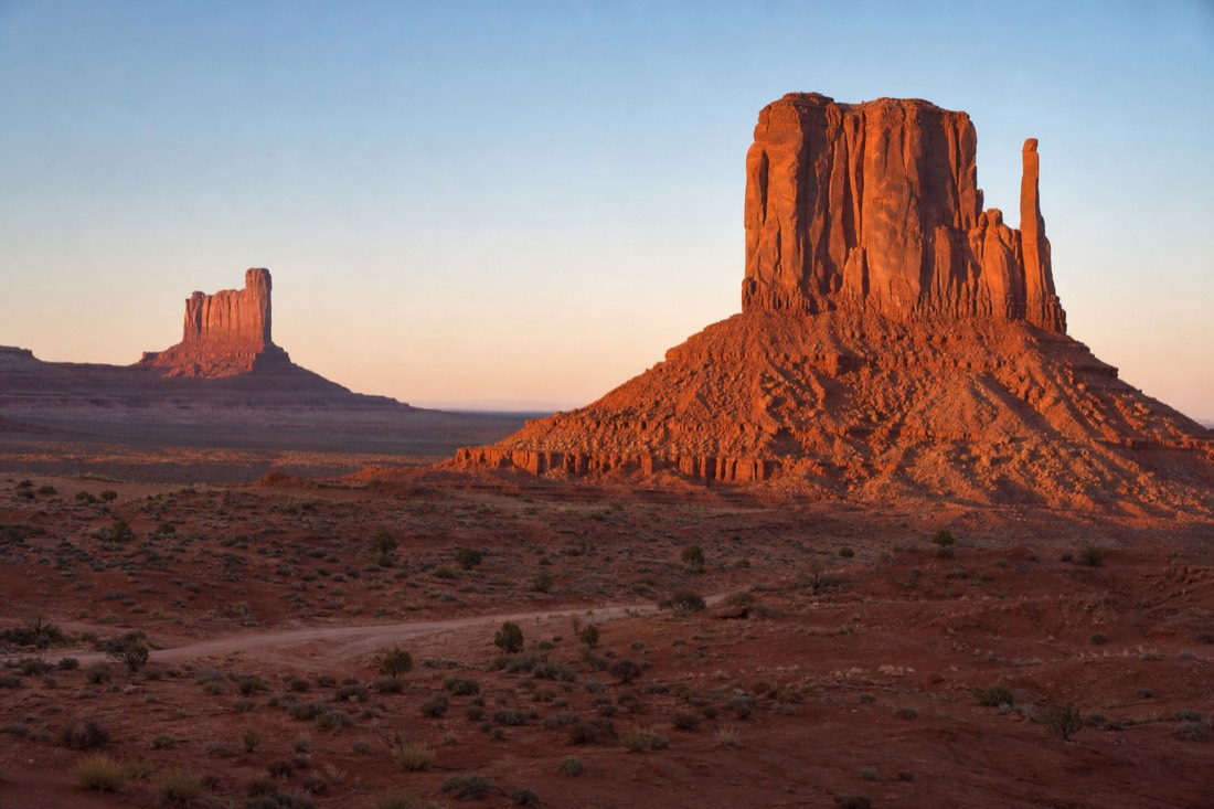 The West and East Mitten Buttes glowing warm red at sunrise on a clear spring morning