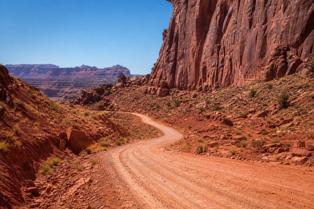 Heat haze shimmering over the empty red dirt Valley Drive under a harsh midday summer sun
