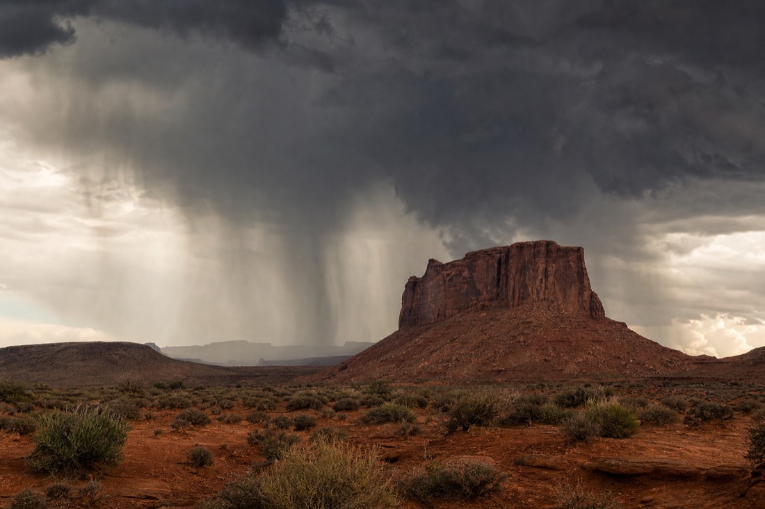 A dark monsoon thunderstorm with curtains of rain sweeping past Merrick Butte in late summer