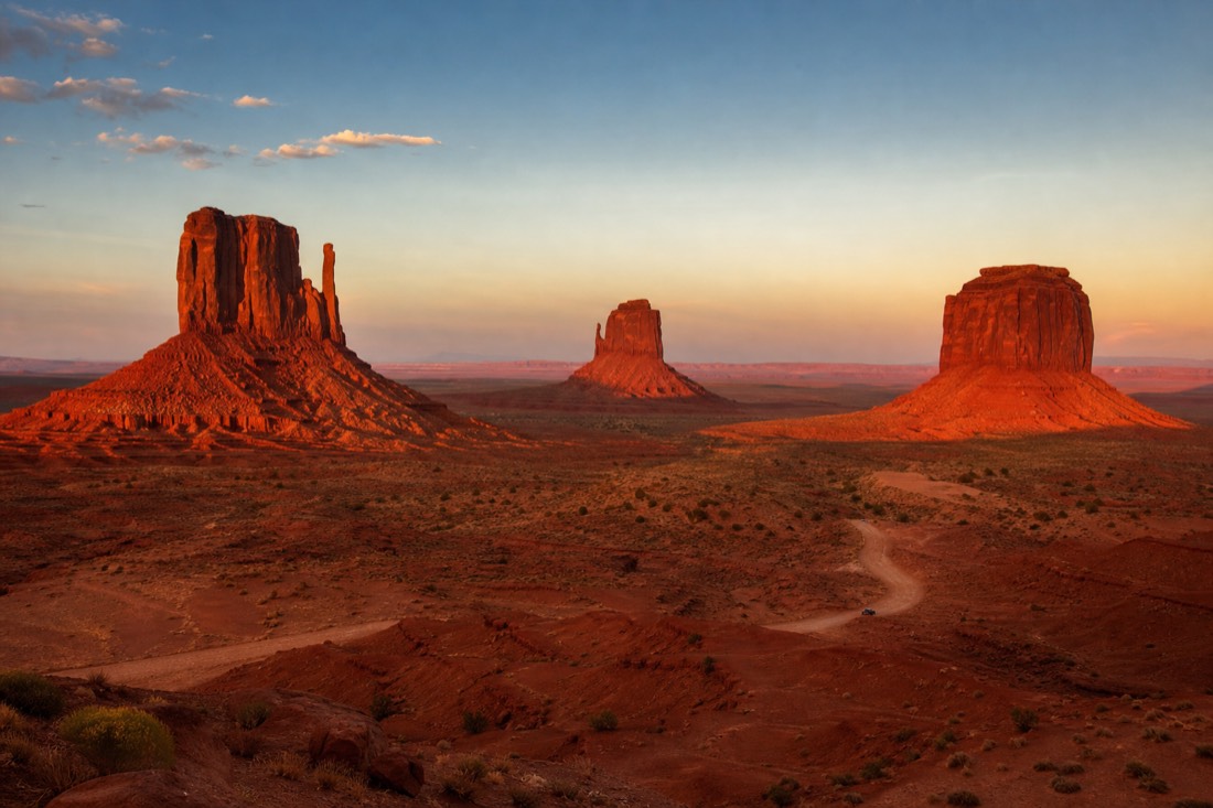 Sunset light turning the Monument Valley buttes deep red across the wide valley floor