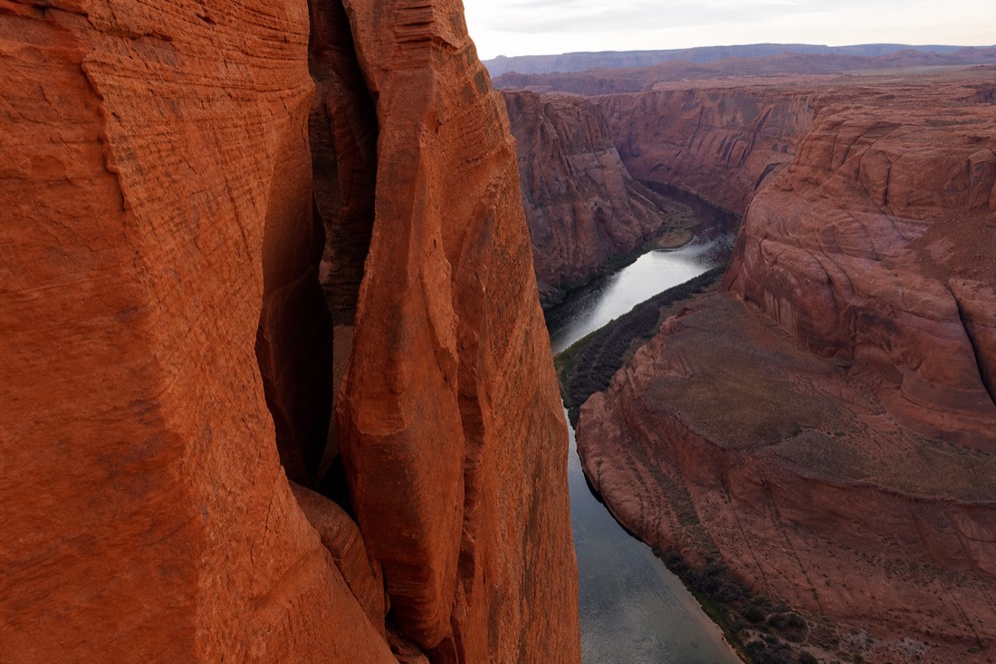 A narrow red slot canyon wall and a sweeping river bend in red sandstone near Page, Arizona