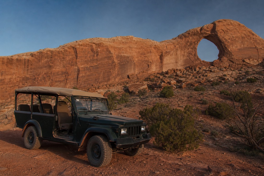 An open-air Navajo guided jeep parked in the backcountry near the Ear of the Wind arch