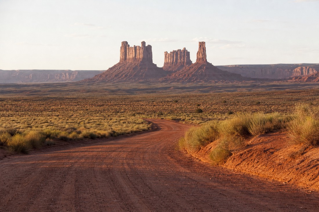 The red dirt entrance road into the Tribal Park with the Mitten Buttes rising straight ahead